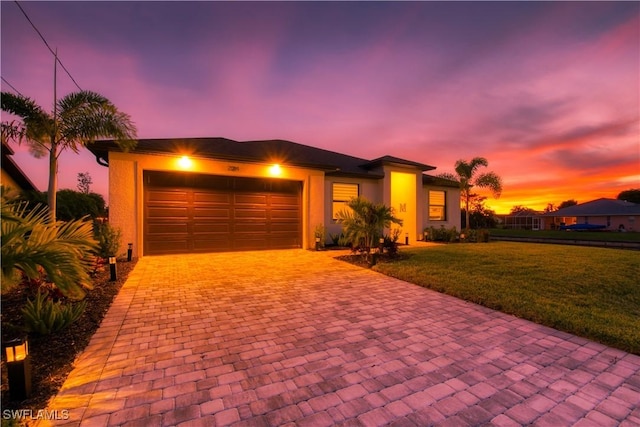 view of front facade featuring decorative driveway, a garage, a front yard, and stucco siding