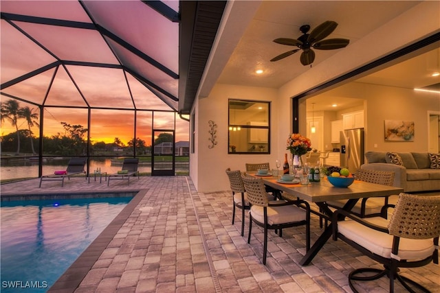 view of patio with an outdoor pool, a ceiling fan, outdoor dining space, and glass enclosure