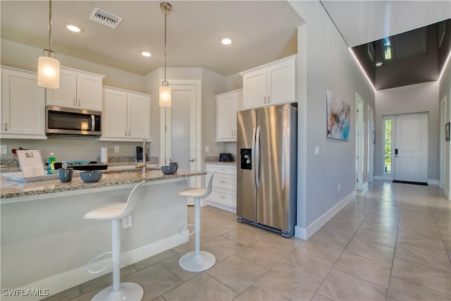 kitchen with stainless steel appliances, white cabinetry, light stone countertops, pendant lighting, and baseboards