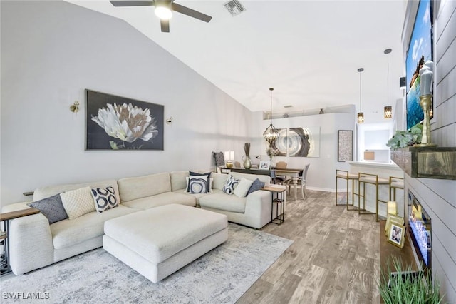 living area with wood finished floors, a ceiling fan, high vaulted ceiling, and baseboards