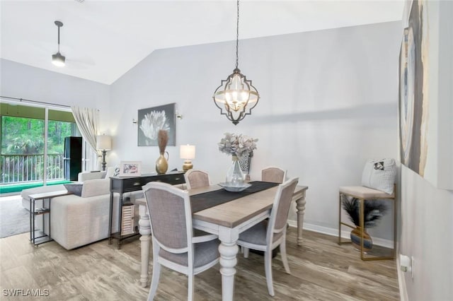dining room with lofted ceiling, a chandelier, wood finished floors, and baseboards