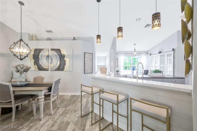 kitchen with wood finished floors, a chandelier, baseboards, lofted ceiling, and a sink