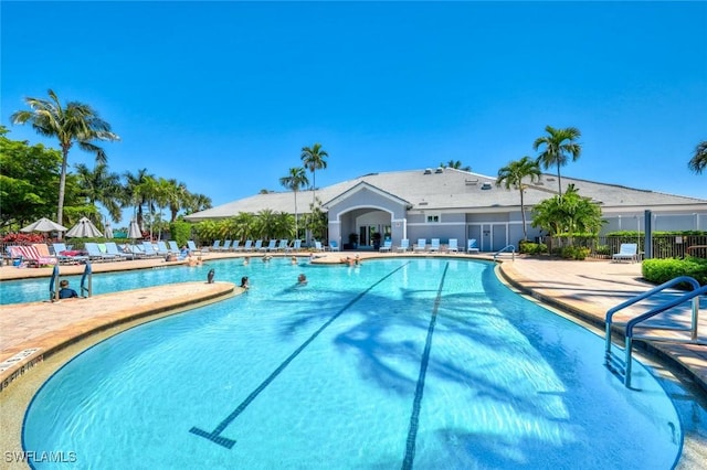 community pool with a patio area and fence
