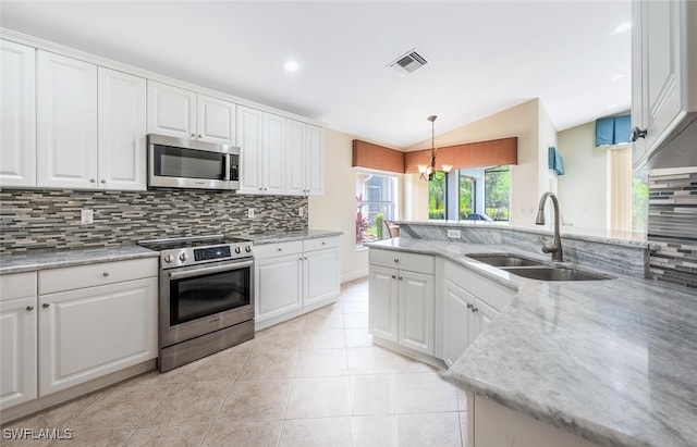kitchen featuring stainless steel appliances, a sink, tasteful backsplash, vaulted ceiling, and white cabinetry