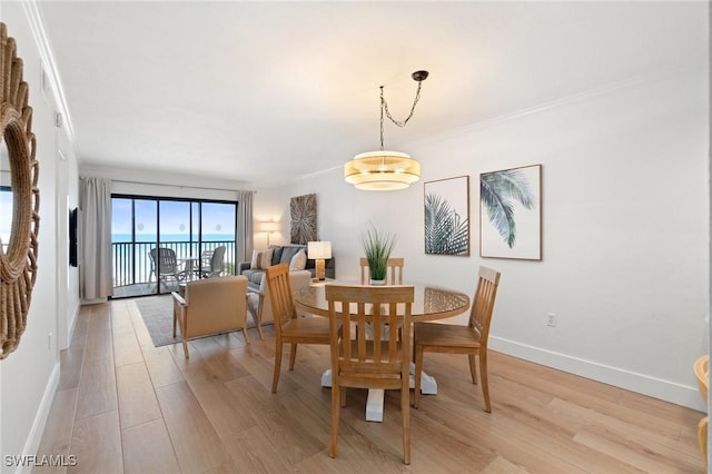 dining area featuring light wood-style floors, ornamental molding, and baseboards