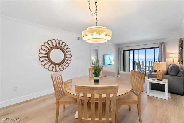 dining space with light wood-style floors, baseboards, and crown molding