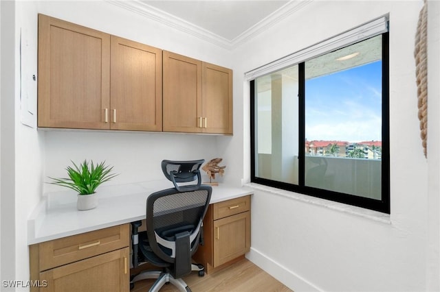 home office featuring built in desk, crown molding, and light wood-style flooring