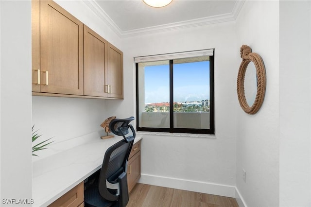 unfurnished office with built in study area, light wood-style floors, baseboards, and crown molding