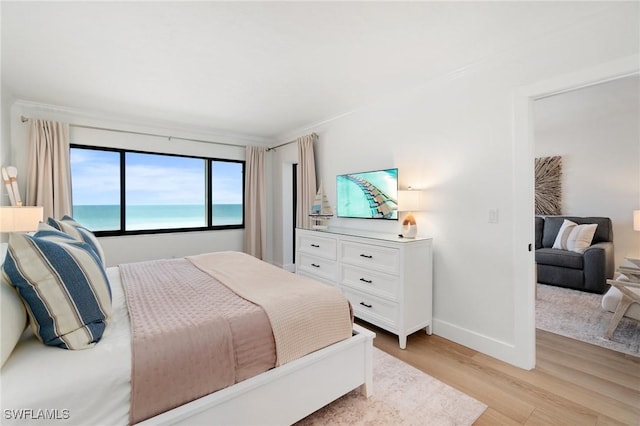bedroom featuring light wood finished floors, baseboards, and crown molding