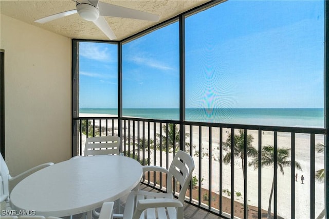 sunroom featuring a wall of windows and view of water and beach