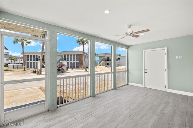 unfurnished sunroom featuring a ceiling fan