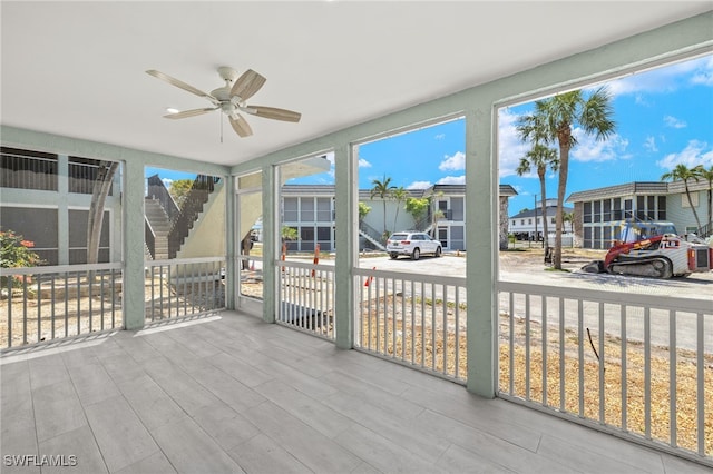 unfurnished sunroom featuring a ceiling fan and a residential view