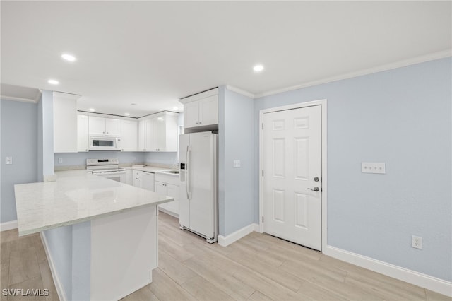 kitchen with white appliances, a peninsula, crown molding, baseboards, and white cabinetry