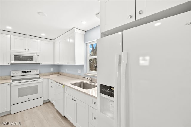 kitchen with white appliances, a sink, white cabinetry, light countertops, and recessed lighting