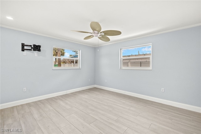 empty room featuring crown molding, healthy amount of natural light, a ceiling fan, and light wood finished floors