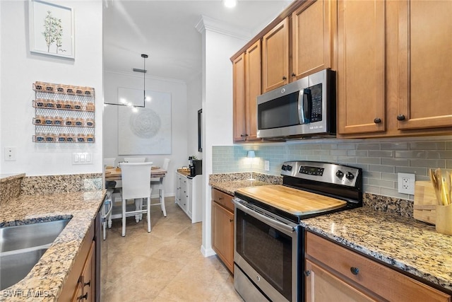 9510 Avellino Way Unit 1924, Naples, FL 34113 - kitchen with appliances with stainless steel finishes, ornamental molding, backsplash, brown cabinets, and light stone counters