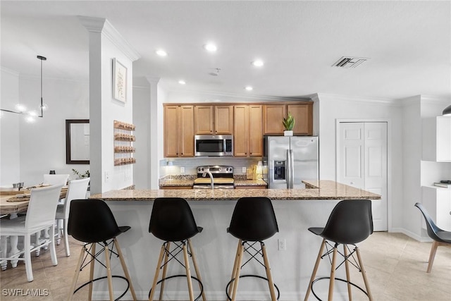 9510 Avellino Way Unit 1924, Naples, FL 34113 - kitchen featuring appliances with stainless steel finishes, crown molding, tasteful backsplash, recessed lighting, and a kitchen breakfast bar