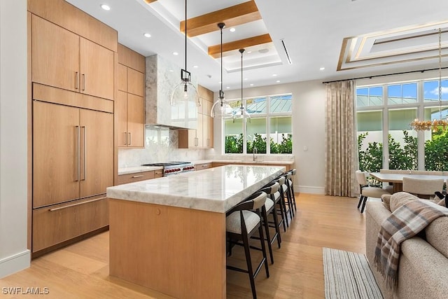 kitchen with paneled fridge, a breakfast bar area, a center island, baseboards, and light stone counters