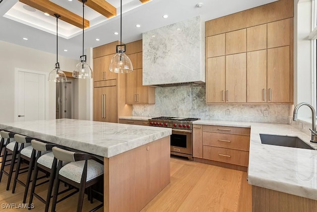 kitchen featuring premium appliances, a sink, light wood-style flooring, light stone counters, and beamed ceiling