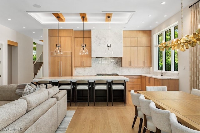 kitchen with paneled refrigerator, open floor plan, light wood-style flooring, light countertops, and a breakfast bar area