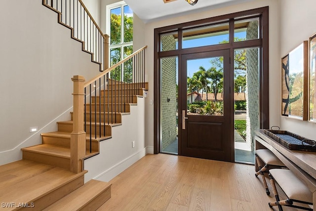 entrance foyer with light wood-type flooring, stairway, and baseboards