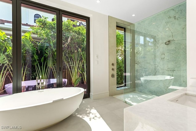 bathroom featuring french doors, a soaking tub, recessed lighting, tile patterned floors, and a sink
