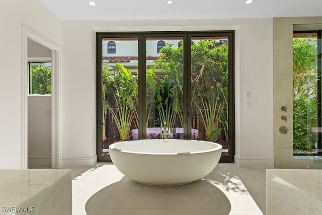 full bathroom with a soaking tub, plenty of natural light, tile patterned floors, baseboards, and recessed lighting