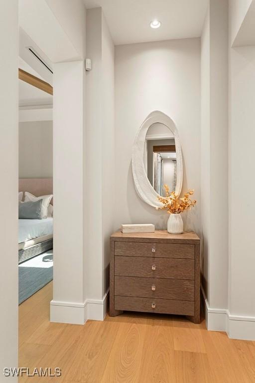 hall featuring light wood finished floors, recessed lighting, and baseboards