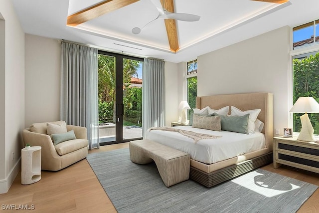 bedroom with a tray ceiling, access to outside, wood finished floors, and a ceiling fan