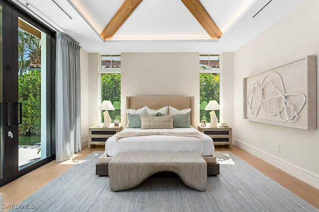 bedroom featuring access to exterior, wood finished floors, multiple windows, and baseboards
