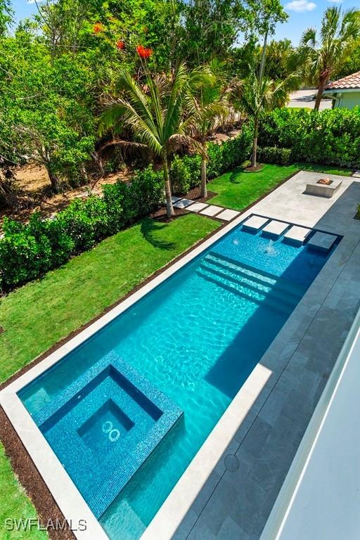 view of pool featuring a yard and a pool with connected hot tub