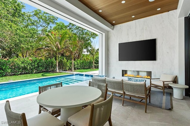 swimming pool with an outdoor living space with a fireplace and a patio area