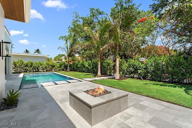 swimming pool with a fire pit, a patio area, and a lawn