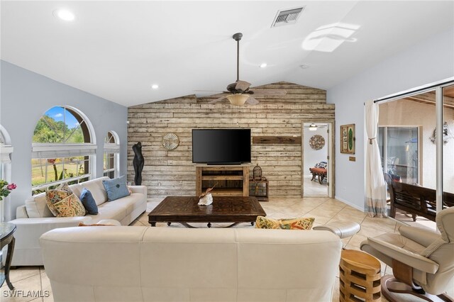 living room featuring lofted ceiling, wood walls, a ceiling fan, light tile patterned flooring, and recessed lighting
