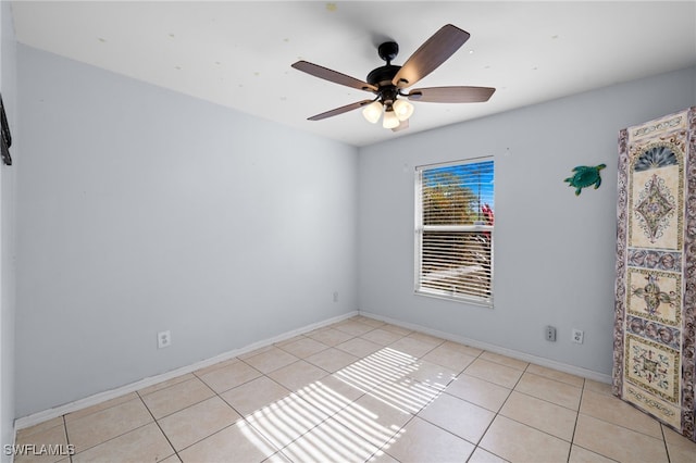 empty room with light tile patterned flooring, a ceiling fan, and baseboards