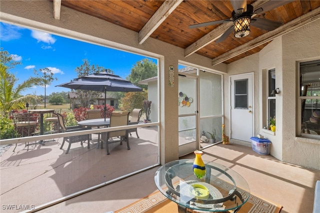 sunroom featuring outdoor dining area, beamed ceiling, a ceiling fan, and plenty of natural light