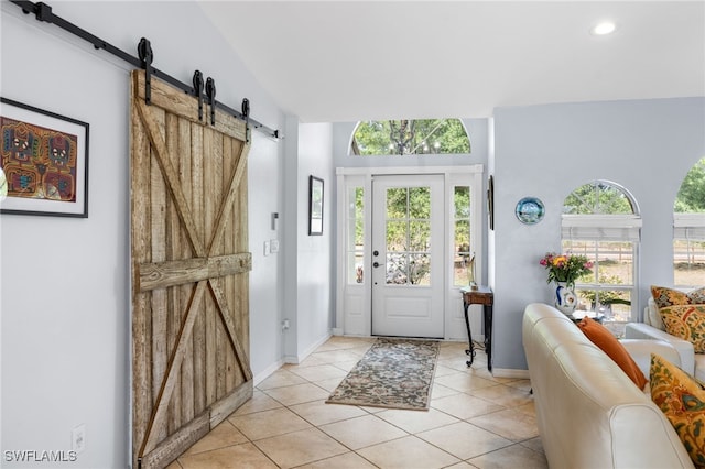 foyer with a barn door, light tile patterned floors, recessed lighting, baseboards, and lofted ceiling