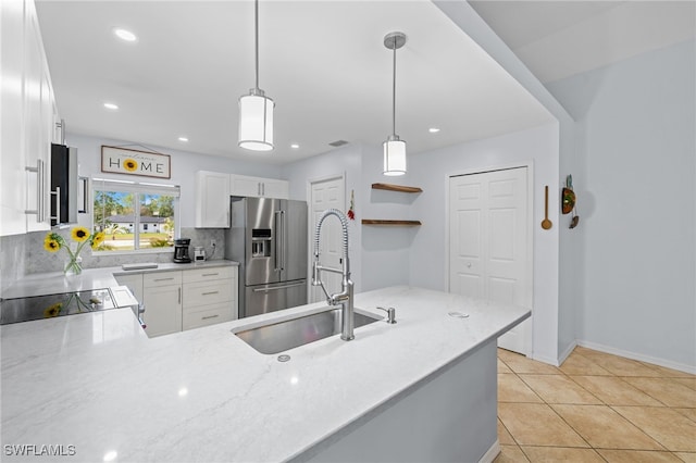 5160 44th St NE, Naples, FL 34120 - kitchen featuring high quality fridge, hanging light fixtures, light stone counters, white cabinetry, and backsplash