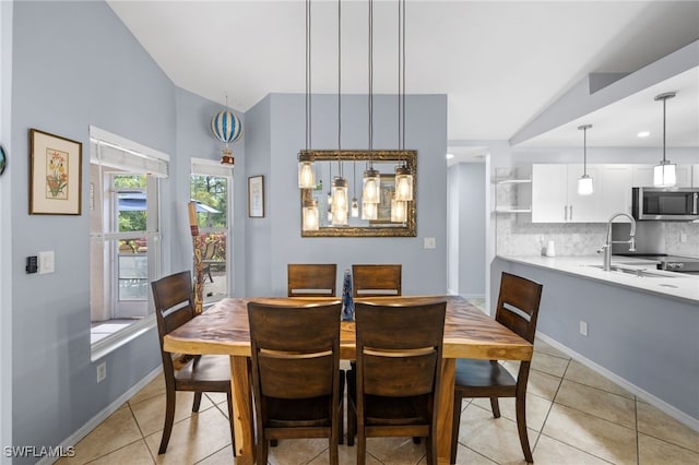 dining room featuring vaulted ceiling, light tile patterned floors, and baseboards