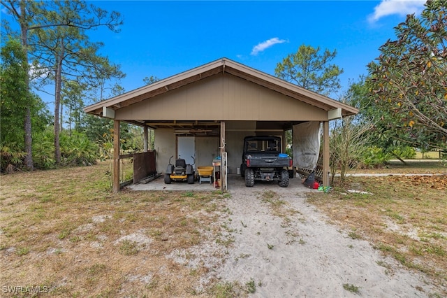 view of outbuilding with dirt driveway and a detached carport