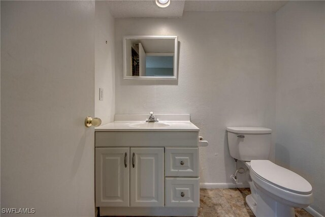 bathroom featuring baseboards, vanity, and toilet