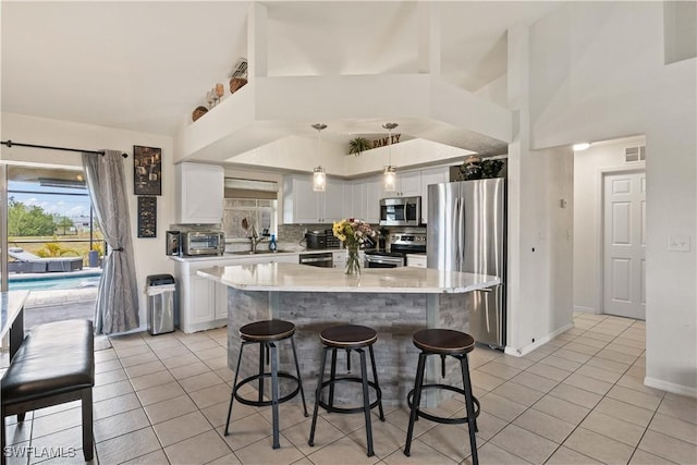 927 NW 12th Ter, Cape Coral, FL 33993 - kitchen featuring appliances with stainless steel finishes, light tile patterned flooring, white cabinets, light countertops, and a breakfast bar