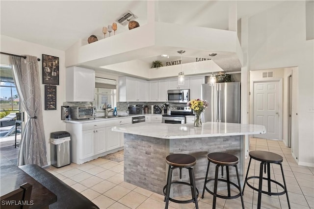 927 NW 12th Ter, Cape Coral, FL 33993 - kitchen with appliances with stainless steel finishes, light tile patterned flooring, a sink, and a kitchen bar