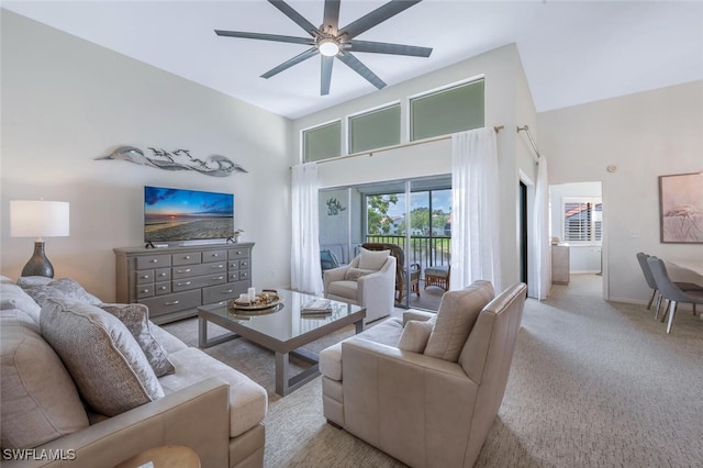 living area featuring a high ceiling, a ceiling fan, carpet floors, and baseboards