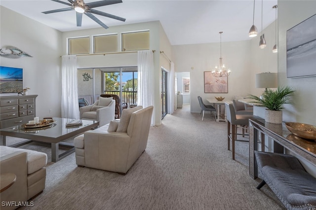 carpeted living area featuring a chandelier, ceiling fan, and a towering ceiling