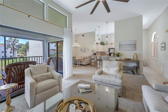 carpeted living room with ceiling fan, a towering ceiling, healthy amount of natural light, and a chandelier