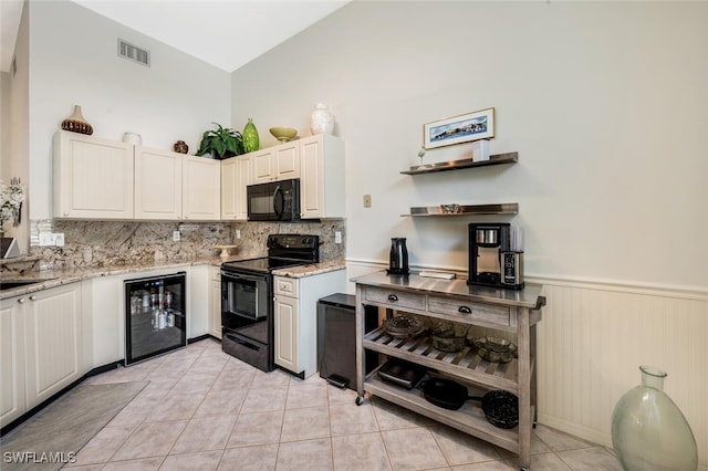 kitchen featuring black appliances, beverage cooler, tasteful backsplash, light tile patterned floors, and a wainscoted wall