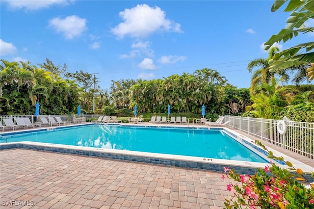 community pool with fence and view of wooded area