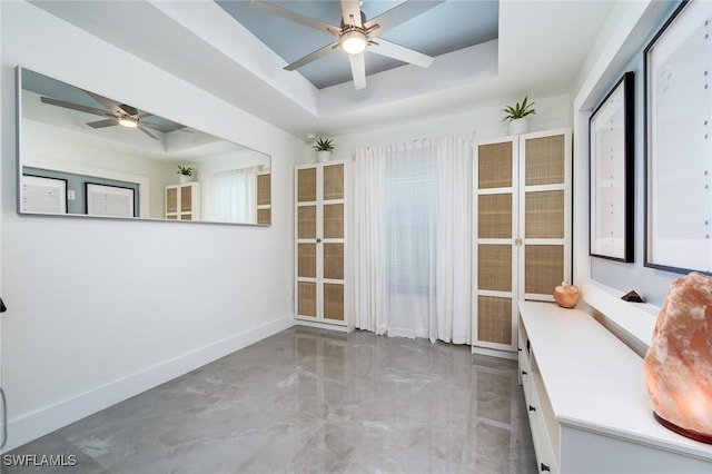spare room with a tray ceiling, ceiling fan, and baseboards