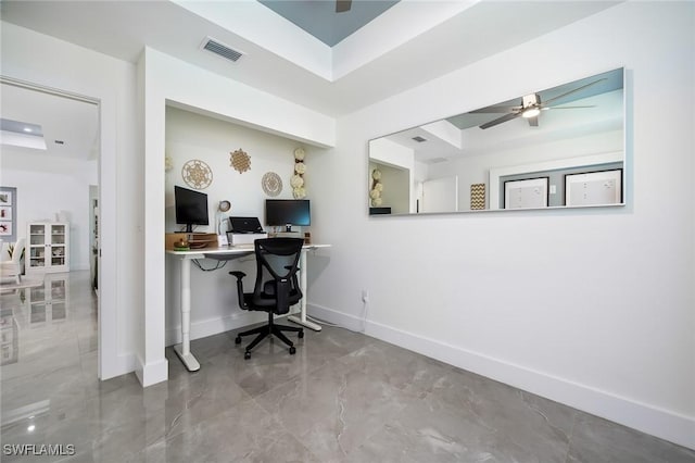 office space featuring a tray ceiling, a ceiling fan, and marble finish flooring